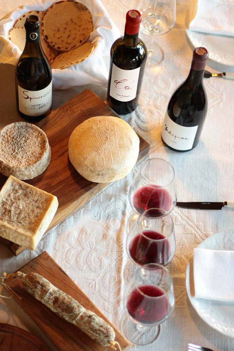 Tavola apparecchiata con i vini del podere, pane, formaggi e salumi della Lunigiana